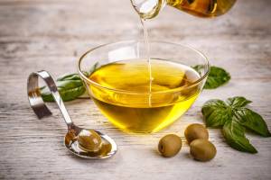 olive oil being poured into glass bowl